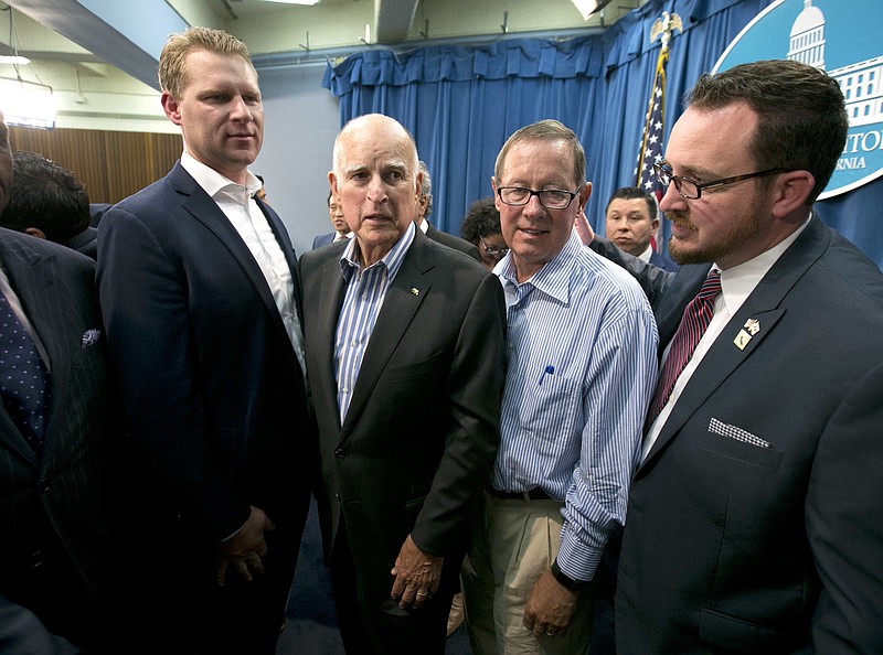 
              Gov. Jerry Brown, center left, flanked by Republicans, Assembly Leader Chad Mayes, of Yucca Valley, left, Tom Berryhill, center right, of Twain Harte, and Devon Mathis, of Visalia, right, leaves a news conference after the Legislature approved a pair of climate change bills, Monday, July 17, 2017, in Sacramento, Calif. Brown was able to get Republican support for the measure, which will extend the state's cap-and-trade program. (AP Photo/Rich Pedroncelli)
            