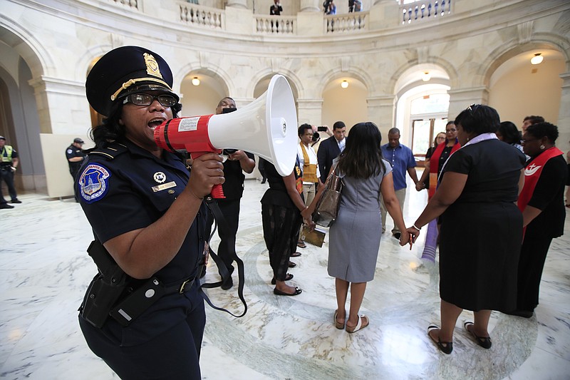 
              A U.S. Capitol Police officer gives the warning speaking through a bullhorn to a group of Black minister gathered to protest on Capitol Hill in Washington, Tuesday, July 18, 2017, demanding Congress to "reject both the immoral budget proposed by the Trump Administration and the equally unjust health care bill that the Senate may have a procedural vote on in the coming weeks." (AP Photo/Manuel Balce Ceneta)
            