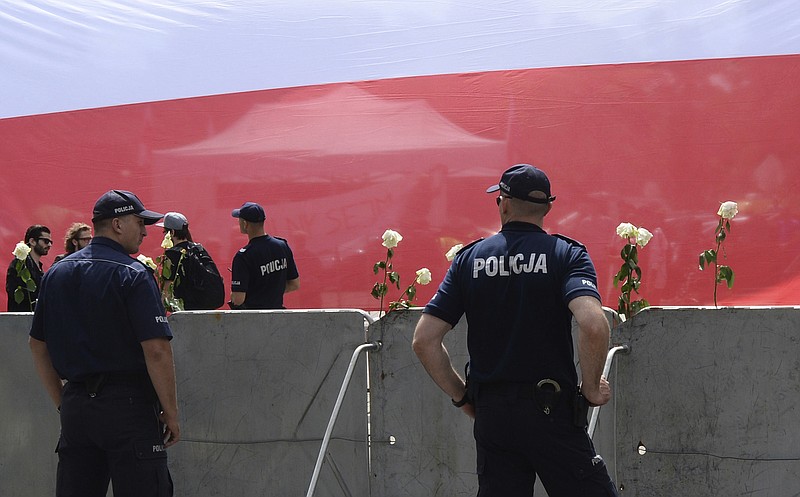 
              A big Polish national flag is spread by protesters in front of the parliament as police officers guard the building in Warsaw, Poland, Tuesday, July 18, 2017. Poland's lawmakers began a heated debate about the controversial draft law by the ruling populist party that will reorganize the work of the Supreme Court, which, the opposition says, will subordinate the court to the justice minister. (AP Photo/Alik Keplicz)
            