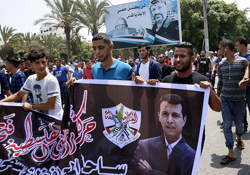 
              Hundreds of supporters of exiled former Gaza strongman Mohammed Dahlan carry a banner with his picture during a protest against metal detectors Israel erected at the Al-Aqsa Mosque compound in Jerusalem, in Gaza City, Thursday, July 20, 2017. A potentially groundbreaking power-sharing deal between two former political foes is slowly unfolding in Hamas-ruled Gaza. In the latest signs of the Egypt-backed understandings moving forward, supporters of Dahlan, a former Hamas nemesis, have been allowed to open a Gaza office and have begun disbursing large sums of Dahlan-procured Gulf aid to Gaza's needy. (AP Photo/Adel Hana)
            