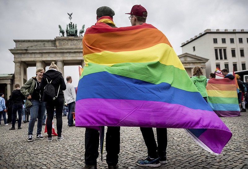 
              CORRECTS TO  GERMAN PRESIDENT SIGNED  LEGISLATION THURSDAY JULY 20, 2017 - FILE - In this June 30, 2017 file photo, men with rainbow flags stand in front of the Brandenburg Gate at an event organized by the Social Democrats to celebrate the legalization of same-sex marriage in Berlin. Germany’s president has signed legislation Thursday July 20,  2017  legalizing gay marriage, paving the way for it to take effect this fall.Lawmakers  approved the bill on June 30 in its last session before Germany’s September election. (Michael Kappeler/dpa via AP,file)
            