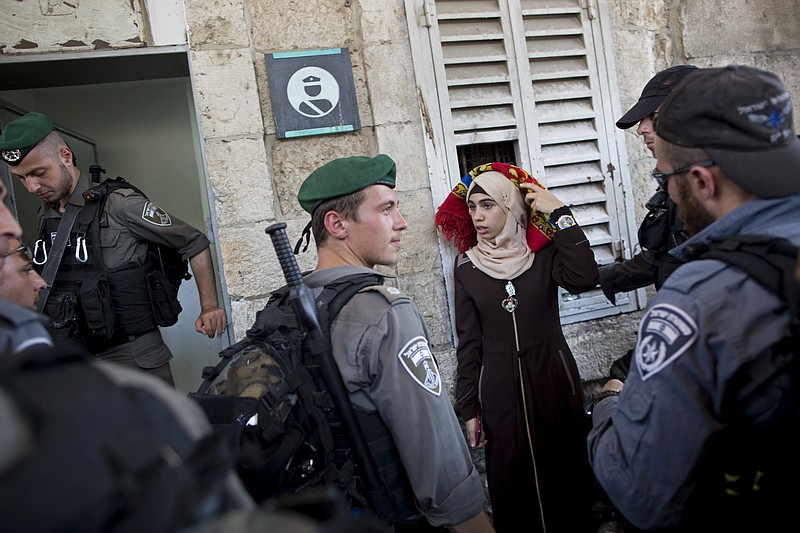 
              Israeli border police officers stop a Palestinian woman for a security check as Palestinians gather for prayer at the Lion's Gate, following an appeal from clerics for Muslims to pray in the streets instead of the Al-Aqsa Mosque compound, in Jerusalem's Old City, Wednesday, July 19, 2017. A dispute over metal detectors has escalated into a new showdown between Israel and the Muslim world over the contested Jerusalem shrine that has been at the center of violent confrontations in the past. (AP Photo/Oded Balilty)
            