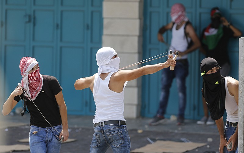 A Palestinian uses a slingshot against Israeli soldiers during clashes in the West Bank city of Bethlehem, Friday, July 21, 2017. Israel police severely restricted Muslim access to a contested shrine in Jerusalem's Old City on Friday to prevent protests over the installation of metal detectors at the holy site.(AP Photo/Nasser Shiyoukhi)