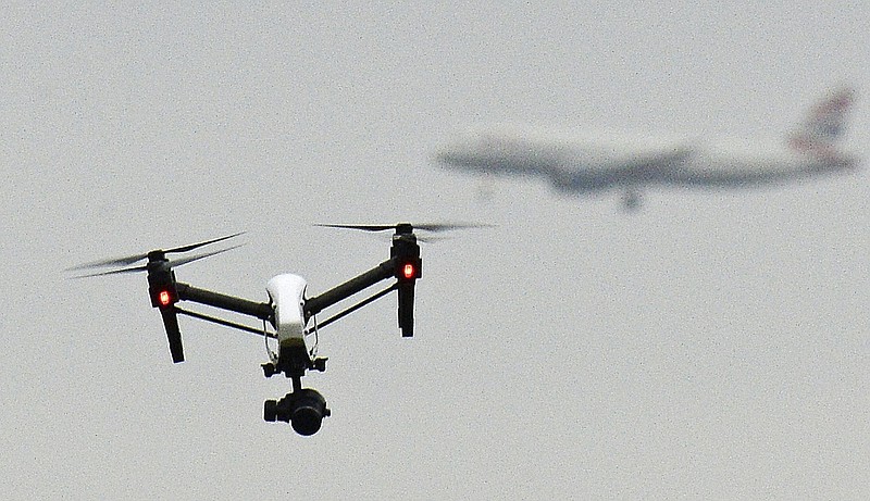 
              FILE - In this Feb. 25, 2017 file photo, a drone flies in Hanworth Park in west London, as a British Airways 747 plane in the background prepares to land at Heathrow Airport. British officials announced plans Saturday, July 22, 2017 to further regulate drone use in a bid to prevent accidents and threats to commercial aviation. (John Stillwell/PA via AP, File)
            