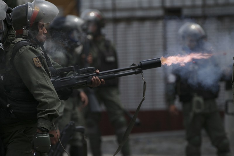 
              A Bolivarian National Guard officer fires tear gas canister aimed at anti-government protesters marching to the Supreme Court to support new magistrates named to the government-dominated Supreme Court by opposition-led led National Assembly, in Caracas, Venezuela, Saturday, July 22, 2017. (AP Photo/Fernando Llano)
            