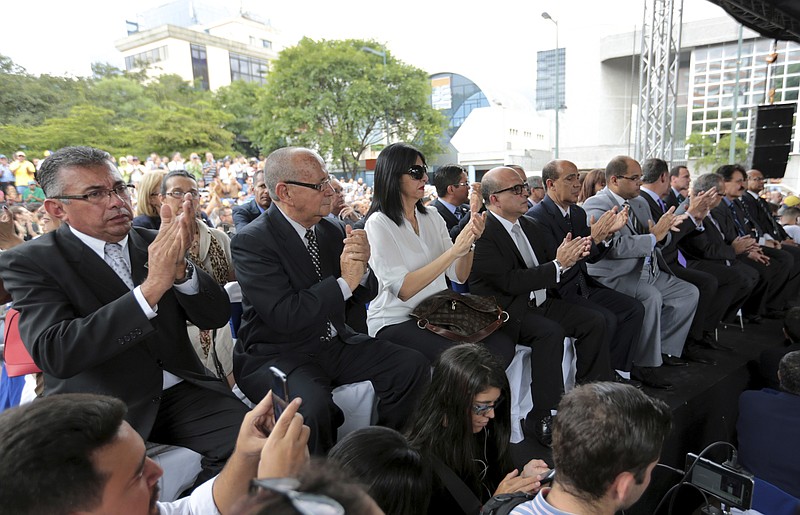 
              Newly-named Supreme Court justices applaud before they are sworn-in at an outdoor ceremony in Caracas, Venezuela, Friday, July 21, 2017. Venezuela's opposition-led National Assembly has sworn in new magistrates to the government-dominated Supreme Court during a ceremony held in a public plaza. They appointed the slate of judges in an escalating fight against President Nicolas Maduro’s plan to rewrite the constitution. (AP Photo/Fernando Llano)
            