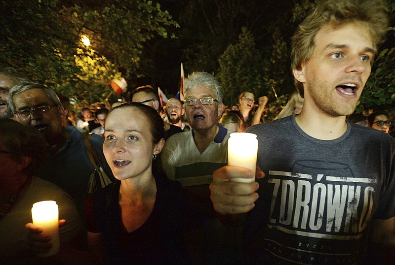 
              Opposition supporters shout slogans and hold candles as they protest in front of the Senate building where a debate continues before a crucial vote to approve legislation that would give politicians substantial influence over the country's Supreme Court, in Warsaw, Poland, Friday, July 21, 2017. The bill on the Supreme Court has drawn condemnation from the European Union and has led to street protests across Poland. (AP Photo/Alik Keplicz)
            