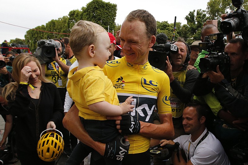 Tour de France winner Britain's Chris Froome, wearing the overall leader's yellow jersey, holds son Kellan as his wife Michelle, left, reacts the Champs Elysees avenue during the twenty-first and last stage of the Tour de France cycling race over 103 kilometers (64 miles) with start in Montgeron and finish in Paris, France, Sunday, July 23, 2017. (AP Photo/Thibault Camus)
