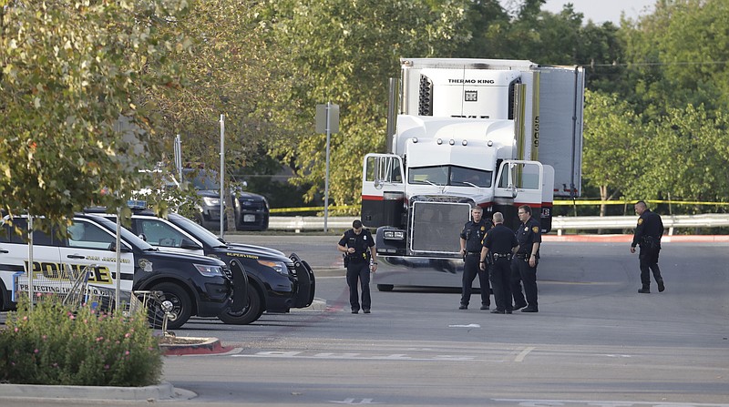
              San Antonio police officers investigate the scene Sunday, July 23, 2017, where eight people were found dead in a tractor-trailer loaded with at least 30 others outside a Walmart store in stifling summer heat in what police are calling a horrific human trafficking case, in San Antonio. (AP Photo/Eric Gay)
            