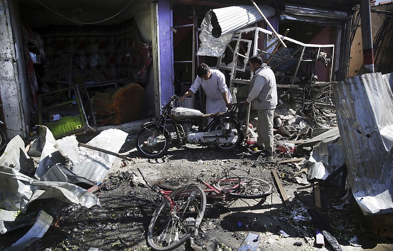 
              Men look at the remains of their properties at the site of a suicide attack in Kabul, Afghanistan, Monday, July 24, 2017. A suicide car bomb killed dozens of people as well as the bomber early Monday morning in a western neighborhood of Afghanistan's capital where several prominent politicians reside, a government official said. (AP Photos/Massoud Hossaini)
            