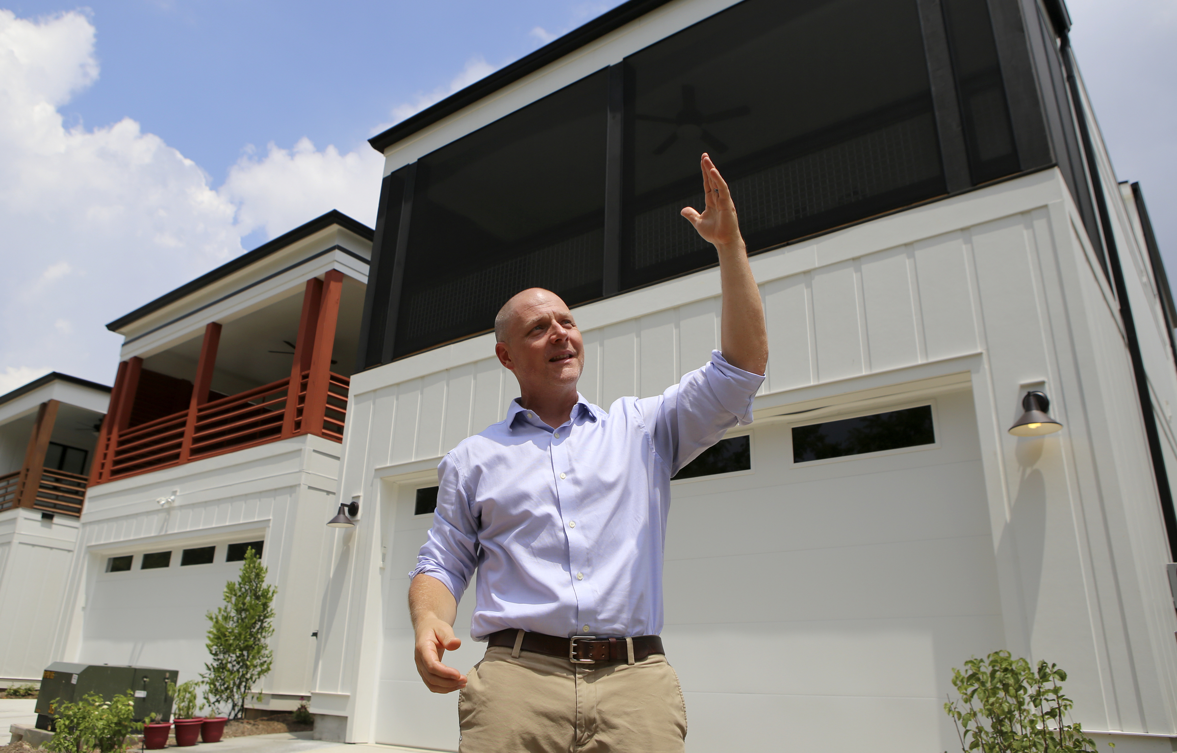 Ethan Collier gives a tour of the new housing development One Hundred at South Broad on Wednesday, July 12, in Chattanooga, Tenn. Some homes, like the one behind Collier, feature a screened porch.