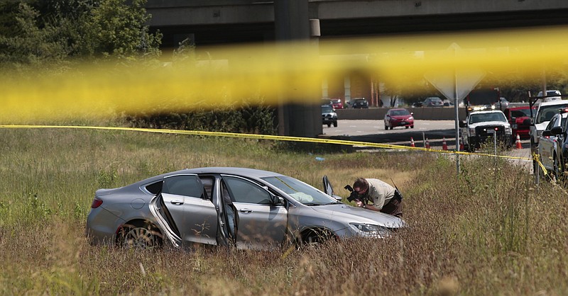 
              A St. Louis County police officer photographs a car surrounded by crime scene tape on Interstate 55 south of Interstate 270 Monday, July 24, 2017. Authorities say a carjacking suspect died Monday after a shootout with police on a busy stretch of interstate near St. Louis.  (Robert Cohen/St. Louis Post-Dispatch via AP)
            