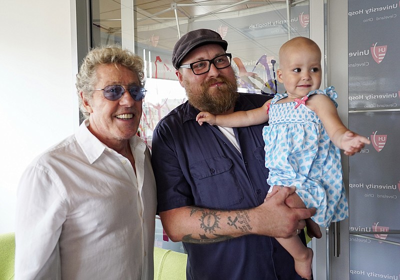 
              Roger Daltrey, lead singer for the English rock band The Who, left, poses with Adam Kirk and his daughter Sawyer McGhee, a cancer patient, in Cleveland, Ohio, on Monday, July 24, 2017.  (AP photo/Dake Kang)
            