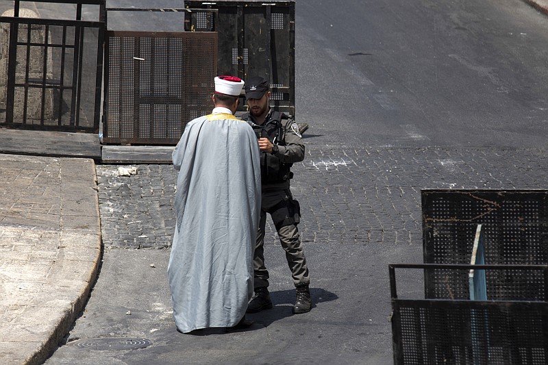 
              An Israeli police officer checks the identification of a Muslim religious man on a main road leading to the Lion's Gate near the Al Aqsa Mosque compound in Jerusalem's Old City, Sunday, July 23, 2017. Israel installed new security cameras Sunday at the entrance to a sensitive Jerusalem holy site, as officials began indicating it was considering "alternatives" to the metal detectors at the contested shrine that set off a weekend of violence and raised tensions in the region. (AP Photo/Ariel Schalit)
            