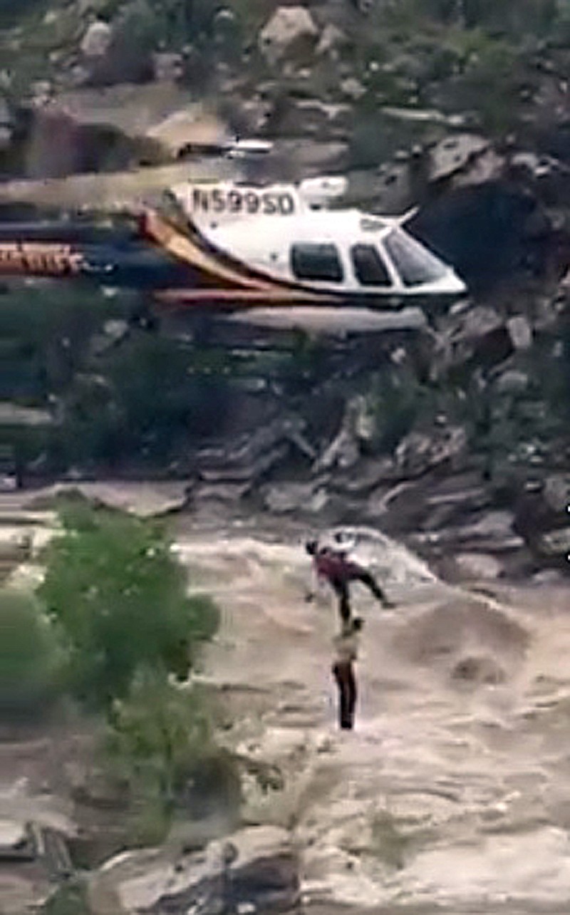 
              In this Sunday, July 23, 2017, image taken from video provided by the Pima County Sheriff's office, a stranded hiker is rescued from torrential flash flood waters near Tucson, Ariz. Over a dozen hikers were stranded Sunday in a scenic canyon on the outskirts of Tucson, just over a week after a flash flood killed 10 members of an extended family more than 140 miles to the north. (Pima County Sheriff via AP)
            