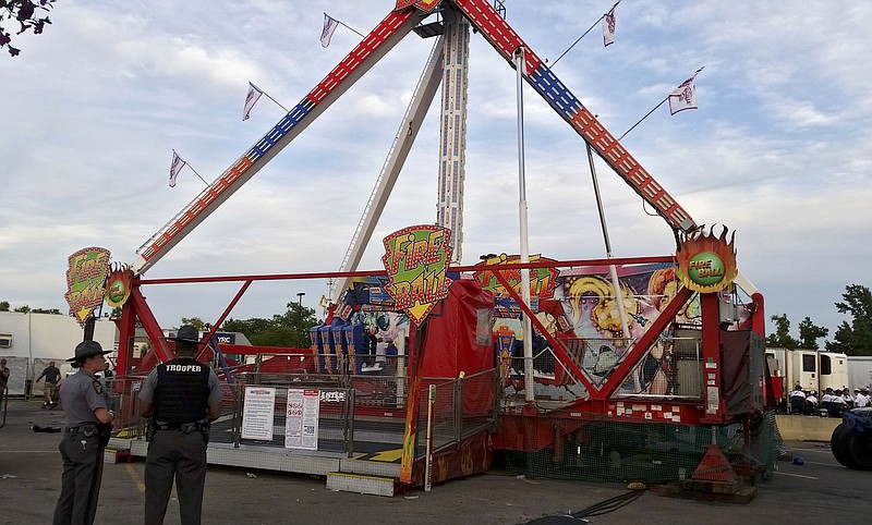 
              Authorities stand near the Fire Ball amusement ride after the ride malfunctioned injuring several at the Ohio State Fair, Wednesday, July 26, 2017, in Columbus, Ohio. Some of the victims were thrown from the ride when it malfunctioned Wednesday night, said Columbus Battalion Chief Steve Martin. (Jim Woods/The Columbus Dispatch via AP)
            