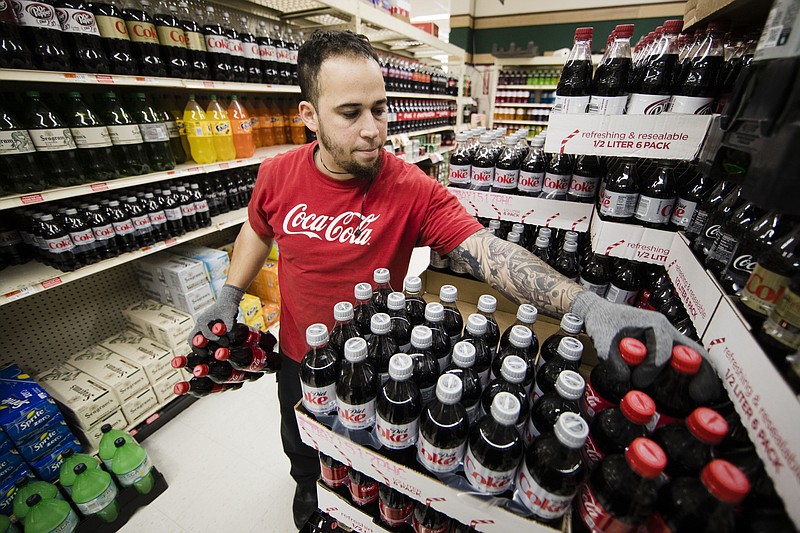 
              FILE - In this March 16, 2017, file photo, Albert Delarosa stocks shelves with Coca-Cola Co. products at the IGA supermarket in the Port Richmond neighborhood of Philadelphia. The Coca-Cola Co. reports earnings, Wednesday, July 26, 2017. (AP Photo/Matt Rourke, File)
            