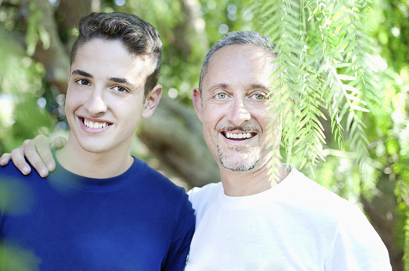 father_proud_confident_serene_and_son_embrace_looking_straight_at_camera_smiling_assured