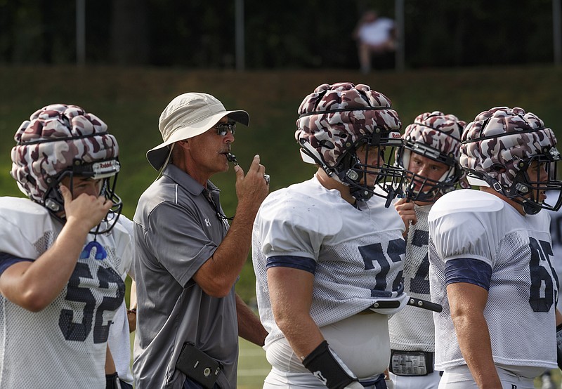 Coach Mark Mariakis directs players who are wearing "guardian caps" over their helmets during the Chargers' football scrimmage at Chattanooga Christian School on Thursday, July 27, 2017, in Chattanooga, Tenn. Guardian caps, which are used to mitigate the effects of concussions and blows to the head in football, are seeing increased use as concerns about head injuries in the sport rise.