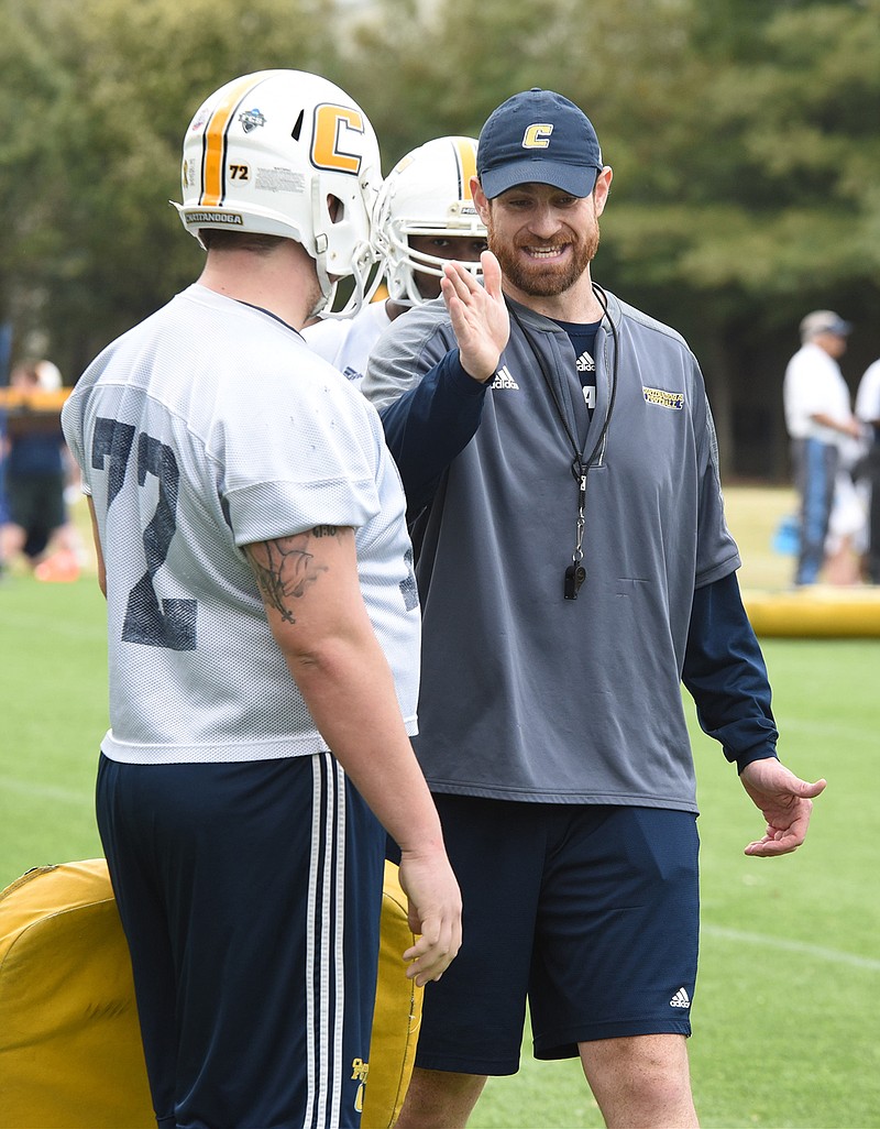 UTC offensive line coach Nick Hennessey talks with senior Josh Cardiello during spring practice.