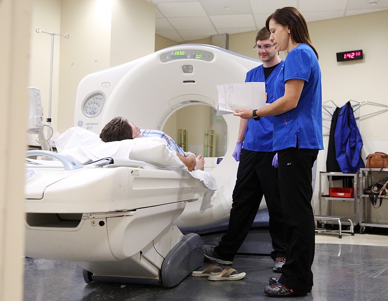 A patient lays on the CT scanner as Christy Sentell, director of imaging services, and Jake Downey, a CT Technologist, speaks with her Friday, July 21, 2017, at CHI Memorial Hospital in Chattanooga, Tenn. CHI Memorial was the first hospital in the country to purchase a software system developed by MedMyne that uses natural language processing to search through medical records to identify the most at-risk population for lung cancer. 