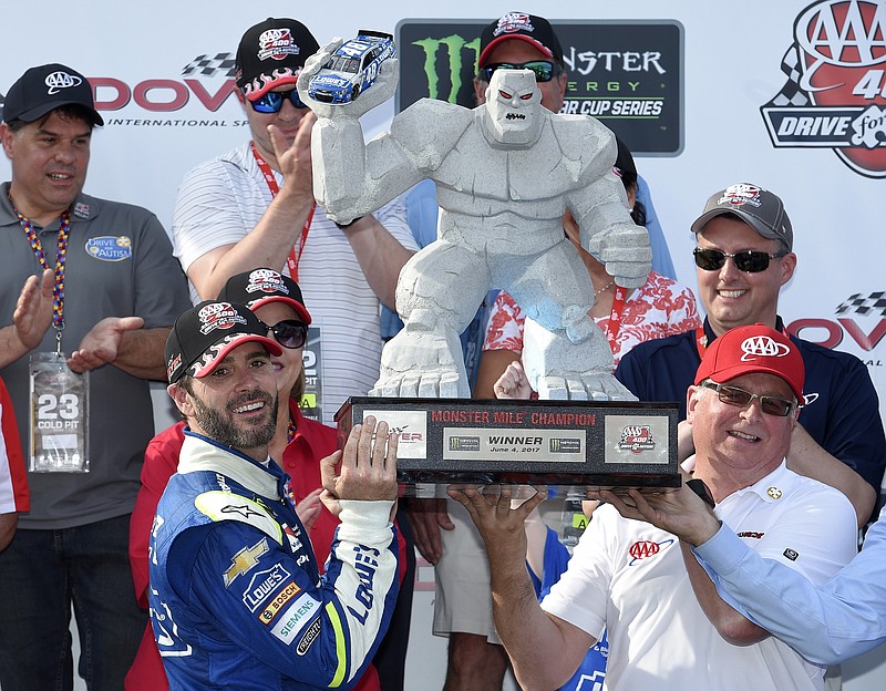 Jimmie Johnson, left, poses with the trophy in victory lane after winning the NASCAR Cup Series race in June at Dover International Speedway in Delaware. Dover's Monster Mile presents Miles the Monster to winning drivers.