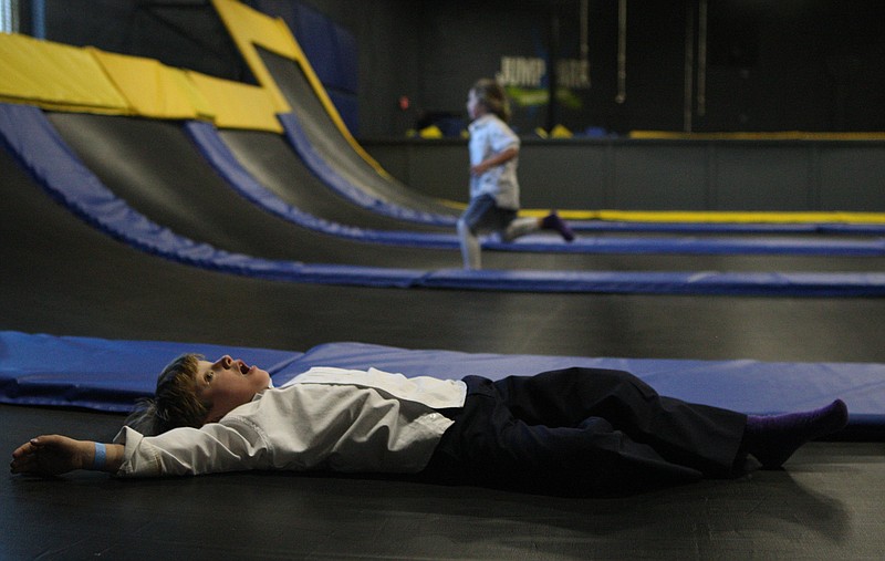 Dallas Jowers, 6, lays exhausted on a trampoline, while his cousin Addison Howard, 6, runs up another trampoline in the background, at the Jump Park.
