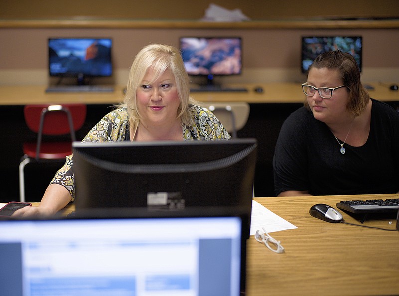 In this Thursday, July 27, 2017, photo, Cheryl Bast, left, is accompanied by her daughter Liz Pierson, as she works on an application for a position with Omaha Public Schools, during a job fair held at Omaha South High School in Omaha, Neb. On Friday, Aug. 4, 2017, the U.S. government issues the July jobs report. (AP Photo/Nati Harnik)

