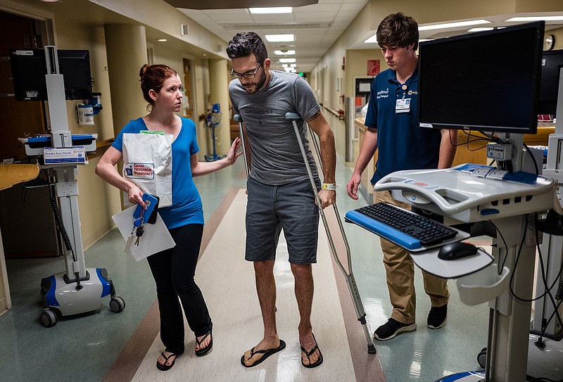 Adam Bunger walks to his car with help from his fiance Sarah Jane Lewis at Erlanger Hospital after his broken hip made it too painful to sit in a wheelchair Friday, June 30, 2017, in Chattanooga, Tenn. Bunger's hip was broken when he was hit by a Ford F150 while riding his bicycle on Dayton Boulevard on June 28.