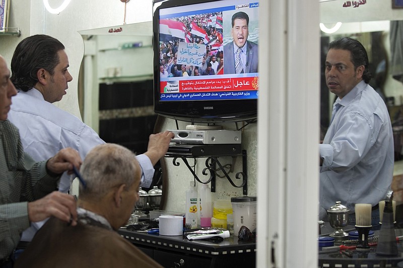 
              FILE - In this May 4, 2011 file photo, a Palestinian barber gives a customer a haircut as a TV set shows a demonstration in Egypt, on the Al Jazeera channel, at a barber shop in Jerusalem's Old city. Israel's communications minister said, Sunday, Aug. 6, 2017, that he wants to shut down pan-Arab broadcaster Al-Jazeera in the country. Ayoob Kara, of Prime Minister Benjamin Netanyahu's Likud party, said he wants the news network's press cards revoked and has asked cable providers to block their transmissions. (AP Photo/Sebastian Scheiner, File)
            