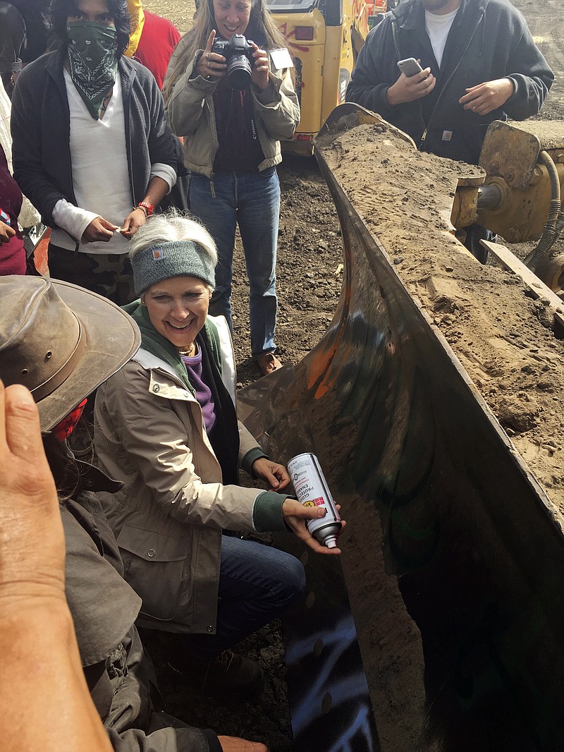 
              FILE - In this Sept. 6, 2016, file photo, Green Party presidential candidate Jill Stein prepares to spray-paint "I approve this message" in red paint on the blade of a bulldozer at a protest against the Dakota Access Pipeline in the area of Morton County, N.D. Stein has reached a plea agreement with prosecutors to resolve criminal charges filed against her in North Dakota nearly a year ago for protesting the Dakota Access oil pipeline, court records show. (Alicia Ewen/KX News via AP, File)
            