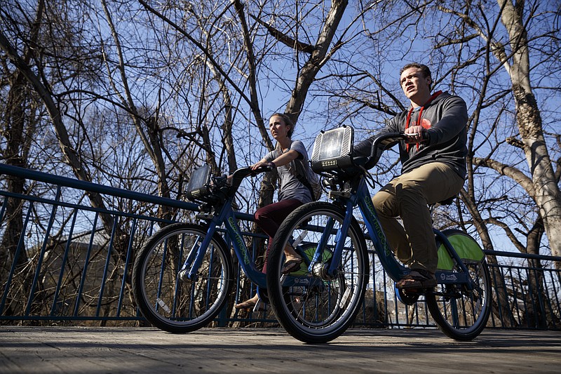 Cyclists ride on the Tennessee Riverwalk, a preserved stretch of land along the Tennessee River foreseen as a public parkway in a 1911 park system report.