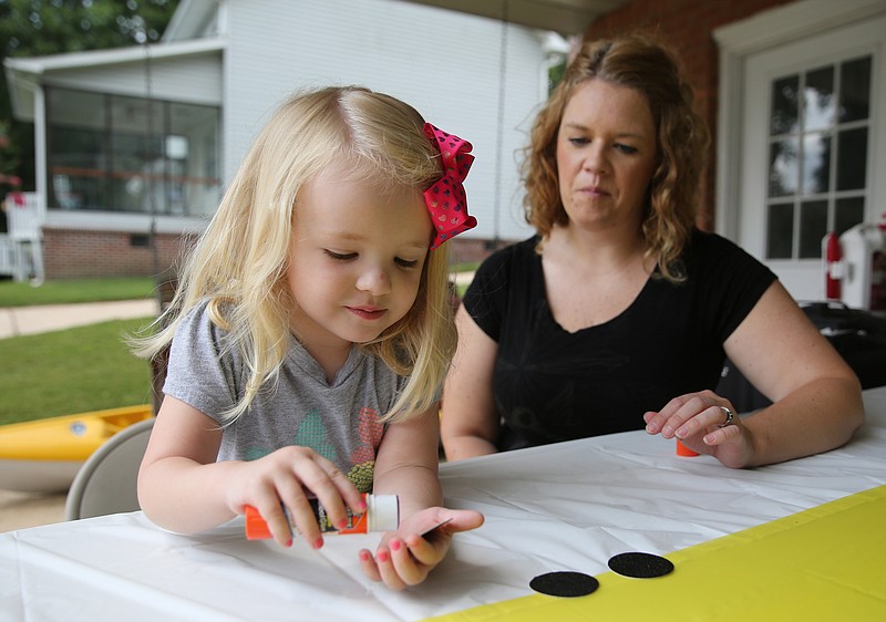Clara Roeser, 3, works on adding moons to a table cloth with the help of her mom Jeana Roeser at Jeana's mom's house Tuesday, Aug. 8, 2017, in Soddy-Daisy, Tenn. The two were helping prepare decorations and souvenirs for guests who attend their family's Great American Eclipse party next week. 