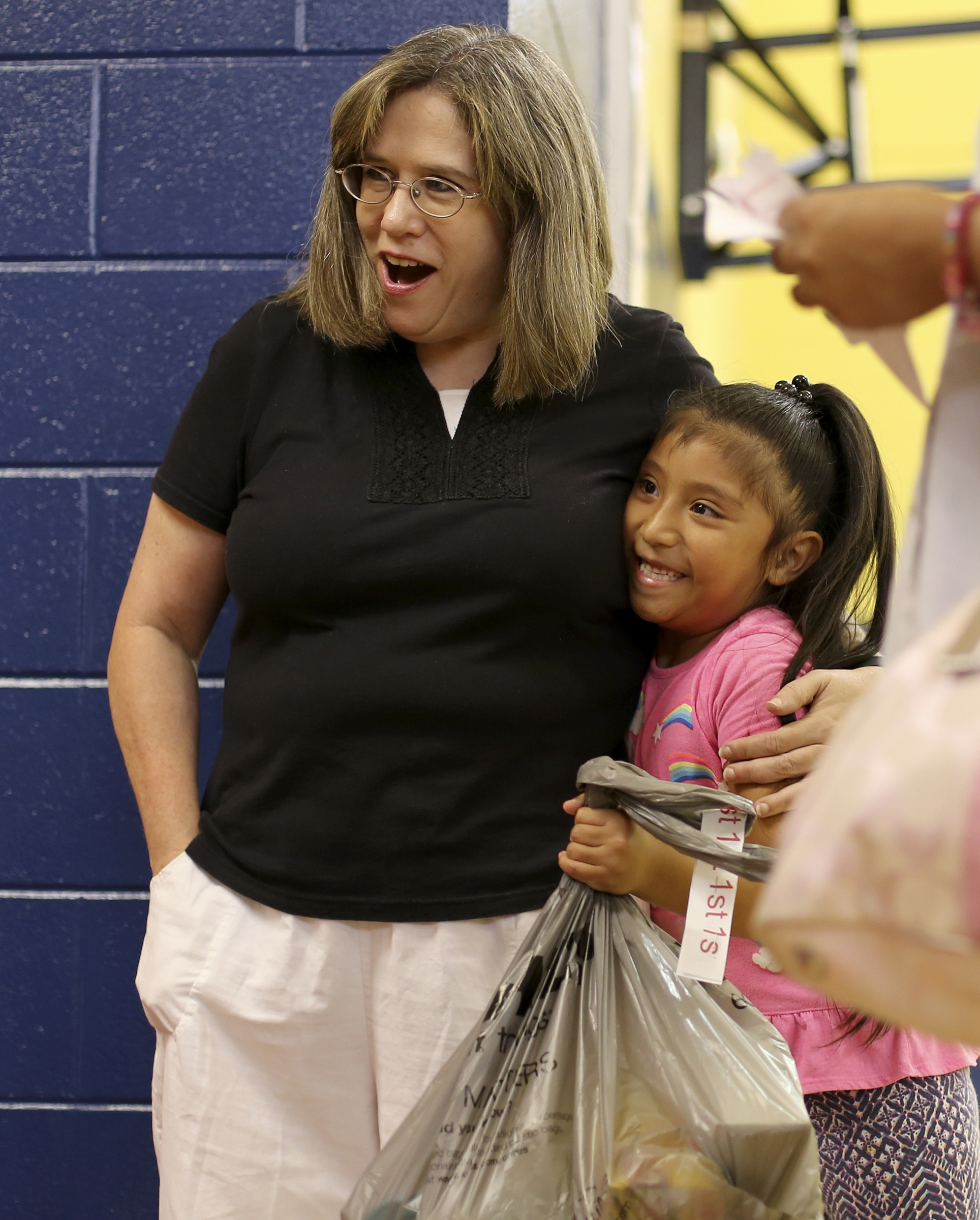 First-grader Viviana Hernandez gives a hug to paraprofessional Jerre Crockett after picking up school supplies at Roan School on Wednesday, Aug. 2, in Dalton, Ga. Roan School, a low-income school, held their orientation on Wednesday and school supplies that were collected and donated by Rock Bridge Community Church were passed out.