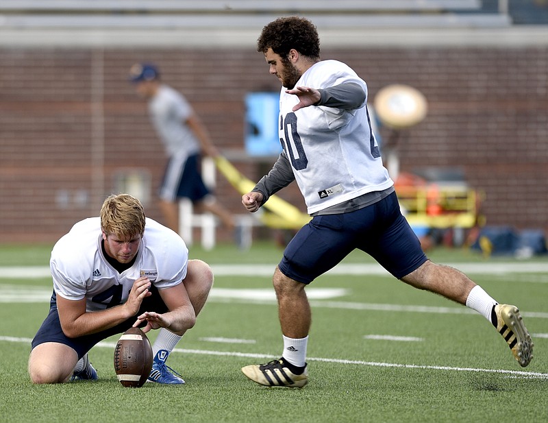 Victor Ulmo kicks from the hold of Colin Brewer in UTC's football practice Thursday at Finley Stadium.