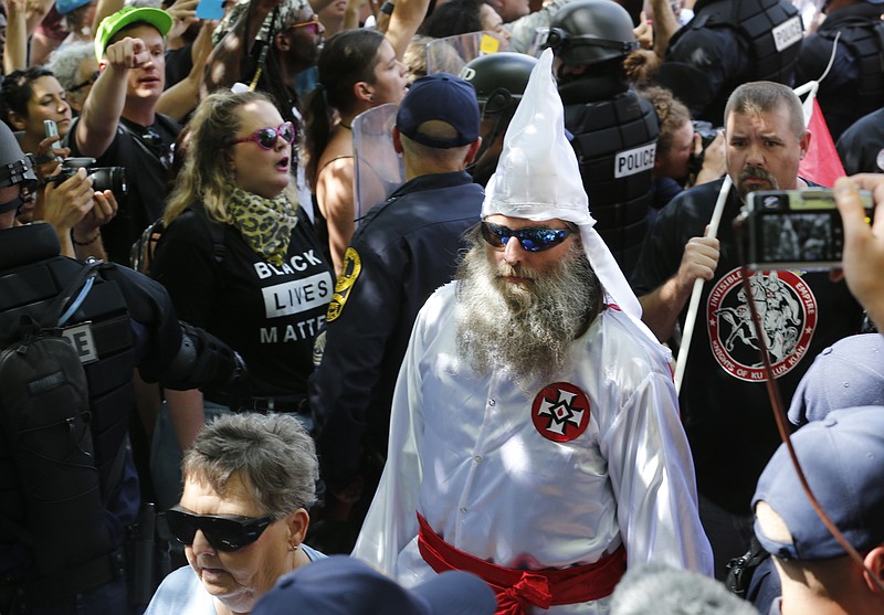 
              This July 8, 2017 photo shows members of the KKK escorted by police past a large group of protesters during a KKK rally in Charlottesville, Va.  Some white Southerners are again advocating for what the Confederacy tried and failed to do in the 1860s: secession from the Union. So-called Southern nationalists are within the group of demonstrators who are fighting the removal of Confederate monuments around the South. They say it’s time for Southern states to secede again and become independent of the United States..(AP Photo/Steve Helber)
            