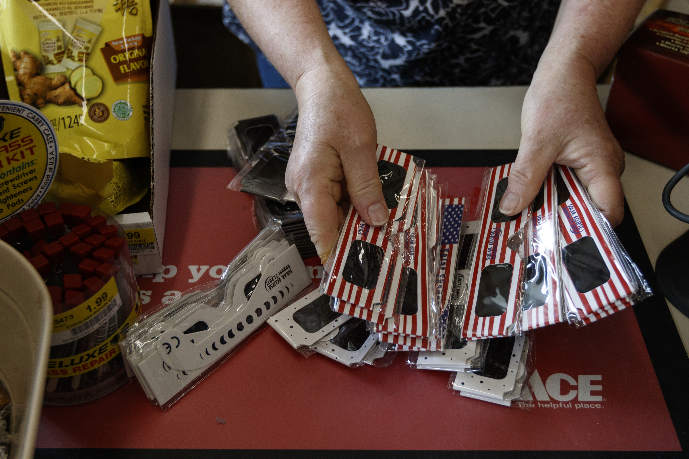 A worker at Ace Hardware fans out eclipse glasses that the store offers for sale on Friday, Aug. 11, 2017, in Spring City, Tenn. On August 21, thousands are expected to flock to the small Rhea County town, which is home to about 2000 residents, to view the solar eclipse.