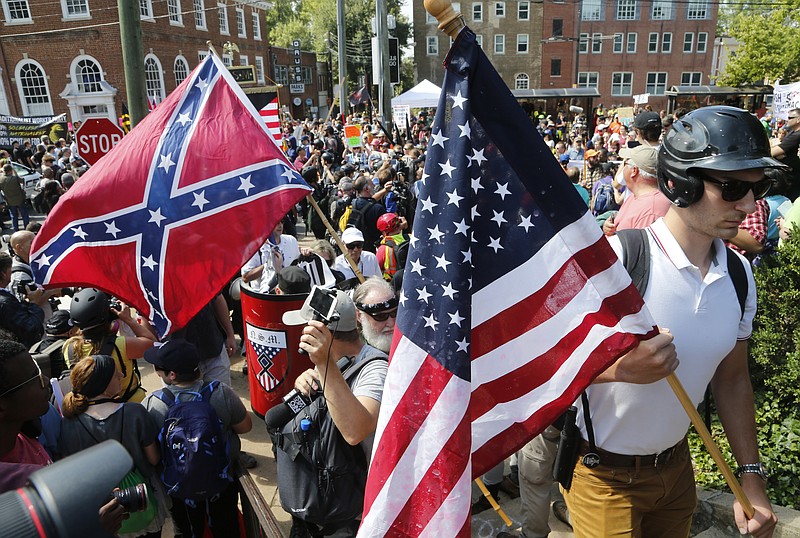 
              White nationalist demonstrators walk into Lee park surrounded by counter demonstrators in Charlottesville, Va., Saturday, Aug. 12, 2017. Gov. Terry McAuliffe declared a state of emergency and police dressed in riot gear ordered people to disperse after chaotic violent clashes between white nationalists and counter protestors. (AP Photo/Steve Helber)
            