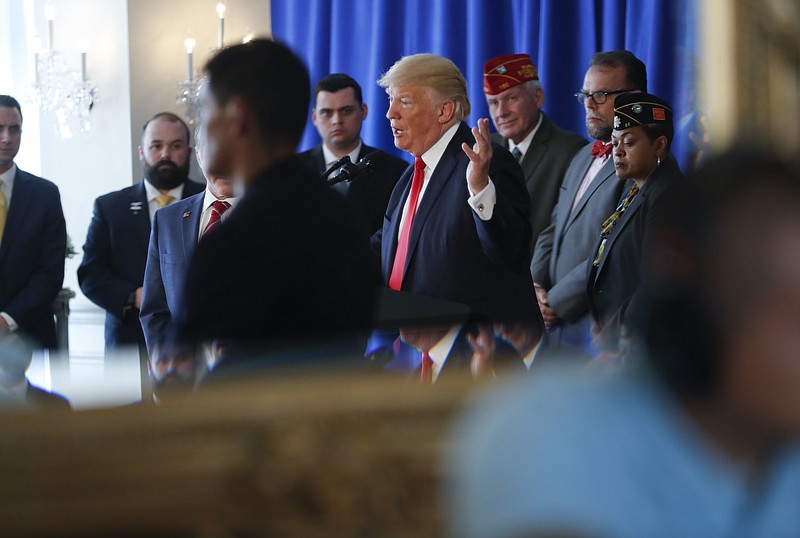 President Donald Trump gestures as he is seen reflected in a ballroom mirror while speaking regarding the on going situation in Charlottesville, Va., Saturday, Aug. 12, 2017 in Bedminister, N.J. Standing behind Trump are military veterans. (AP Photo/Pablo Martinez Monsivais)