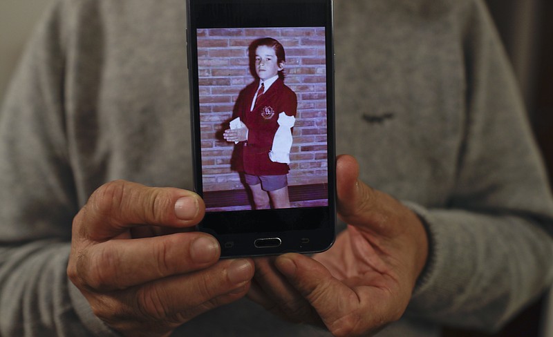 
              In this July 4, 2017 photo, Rufino Varela shows a portrait of himself on his cell phone when he was 9-years-old, during his first communion ceremony in 1974 at the Cardenal Newman school in Buenos Aires, Argentina. After nearly four decades, Varela broke his silence about sexual abuse he suffered at the hands of Rev. Finnlugh Mac Conastair at the school when he was 12 years old, which has led several other former students to denounce clerical abuse at a school that has educated President Mauricio Macri and many other members of Argentina's elite. (AP Photo/Natacha Pisarenko)
            