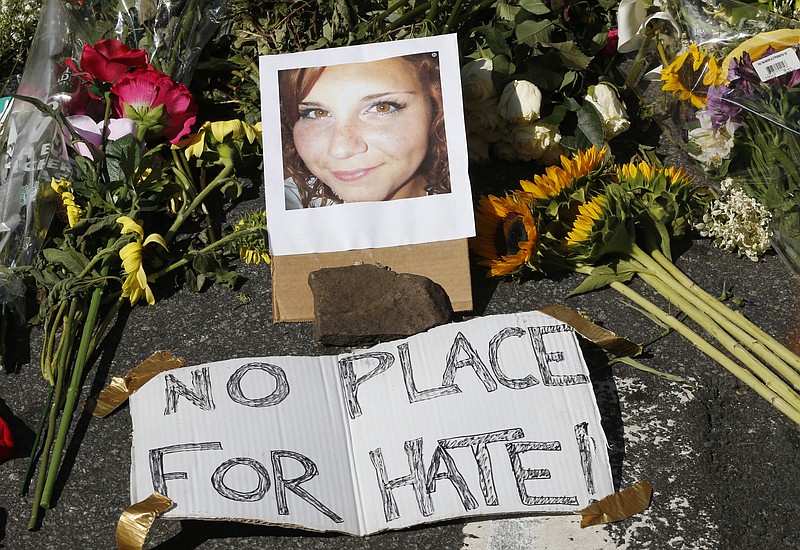 A makeshift memorial of flowers and a photo of victim, Heather Heyer, sits in Charlottesville, Va., Sunday, Aug. 13, 2017. Heyer died when a car rammed into a group of people who were protesting the presence of white supremacists who had gathered in the city for a rally. (AP Photo/Steve Helber)