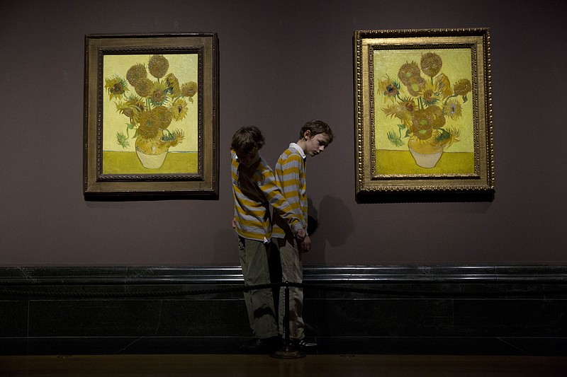 
              FILE - In this Friday, Jan. 24, 2014 file photo, twins Edgar, left, and Gabriel, aged 10, arrange themselves to pose for photographers beside two versions of Dutch-born painter Vincent van Gogh's "Sunflowers", the left one from 1888 and the right one from 1889, during a photocall at the National Portrait Gallery in London. Five versions of a Vincent van Gogh masterpiece are being reunited for the first time in a “virtual exhibition.” On Monday, Aug. 14, 2017, they will all be streamed to a global audience in a Facebook Live broadcast. (AP Photo/Matt Dunham, File)
            