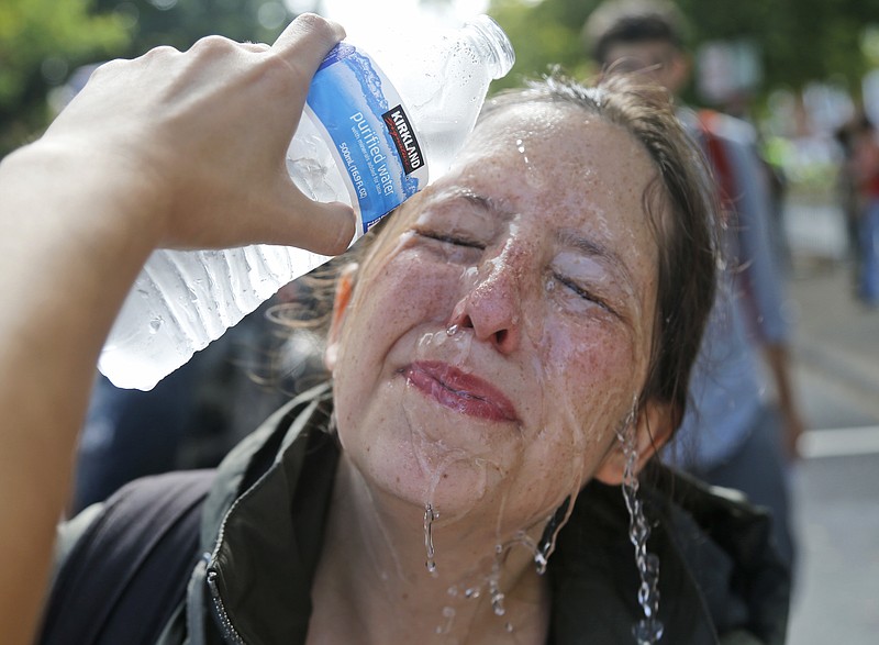 
              A counter demonstrator gets a splash of water after being hit by pepper spray at the entrance to Lee Park in Charlottesville, Va., Saturday, Aug. 12, 2017. Gov. Terry McAuliffe declared a state of emergency and police dressed in riot gear ordered people to disperse after chaotic violent clashes between white nationalists and counter protestors. (AP Photo/Steve Helber)
            