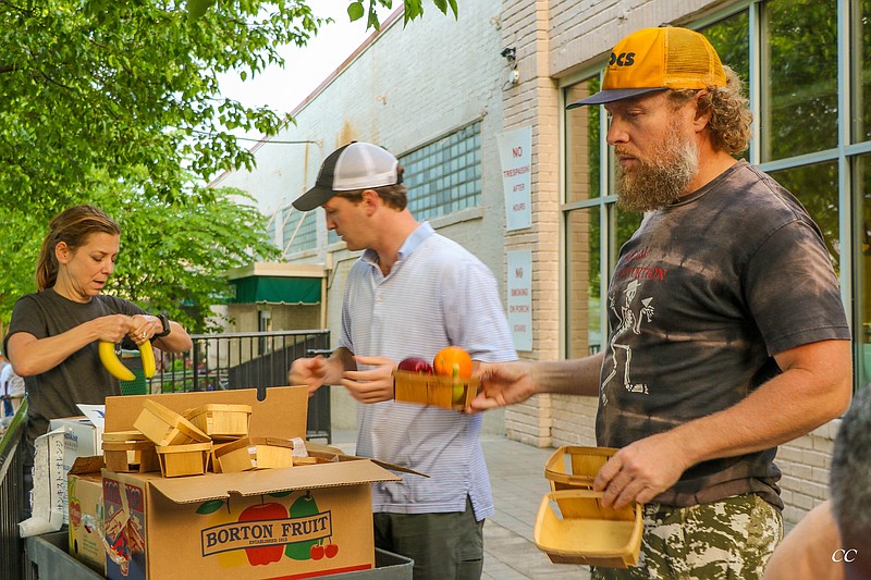 Elaine Burt, Asa Swift and Robert Gustafson, from left, unpack fruit from Swift's I Love Juice Bar that he donated to the Community Kitchen. (Contributed photo)
