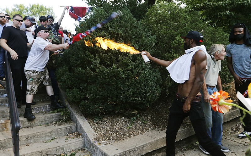 
              A counter demonstrator uses a lighted spray can against a white nationalist demonstrator at the entrance to Lee Park in Charlottesville, Va., Saturday, Aug. 12, 2017.   Gov. Terry McAuliffe declared a state of emergency and police dressed in riot gear ordered people to disperse after chaotic violent clashes between white nationalists and counter protestors. (AP Photo/Steve Helber)
            