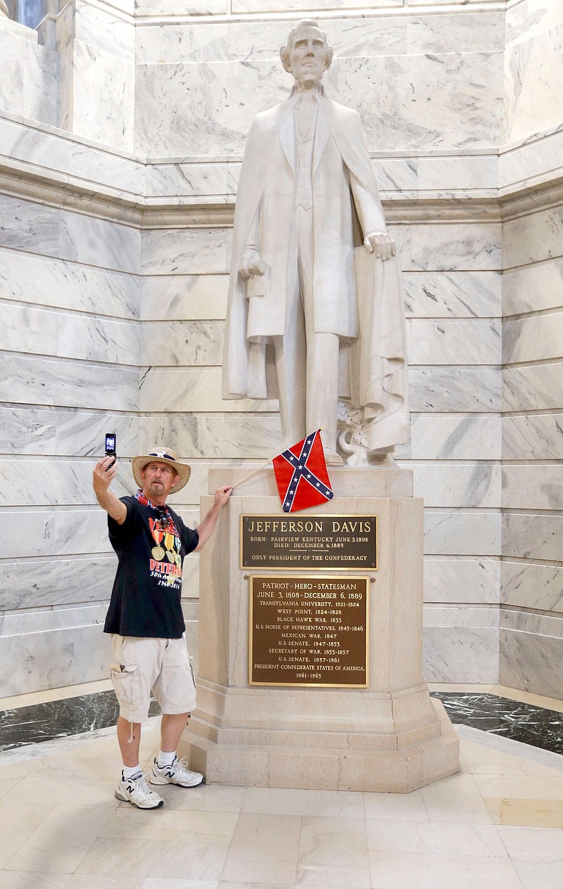 
              This photo taken July 24, 2017, shows James Hendrickson, Corbin, Ky., taking a "selfie" with the Jefferson Davis Statue following a rally in support of keeping the statue of Confederate president Jefferson Davis in the Capitol, held on the steps of the State Capitol in Frankfort, Ky. The Kentucky chapter of the Sons of Confederate Veterans organized the rally. After the photo, he attached the flag to the statue. Kentucky's NAACP is renewing efforts to have the statue removed from the Capitol Rotunda in the aftermath of deadly violence in Charlottesville, Va. (Charles Bertram/Lexington Herald-Leader via AP)
            