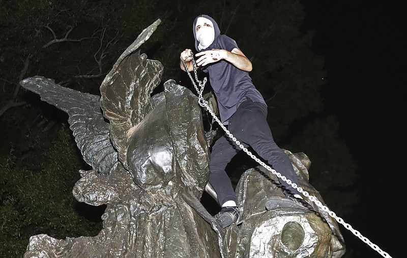 
              A protester climbs a Confederate monument with a chain in an attempt to topple it Sunday, Aug. 13, 2017, in Atlanta. The peace monument at the 14th Street entrance depicts an angel of peace stilling the hand of a Confederate soldier about to fire his rifle. Protesters decrying hatred and racism converged around the country on Sunday, saying they felt compelled to counteract the white supremacist rally that spiraled into deadly violence in Virginia. (Curtis Compton/Atlanta Journal-Constitution via AP)
            