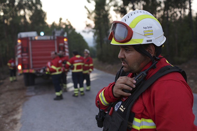 
              In this photo taken on Thursday, Aug. 10 2017, Hugo Simoes talks on the radio while coordinating a group of volunteer firefighters from Lisbon helping fight a forest fire near the village of Aldeia do Monte outside Abrantes, central Portugal. Almost all of the 2,000 Portuguese firefighters at a weeklong wildfire that killed more than 60 people this summer had something in common apart from the acute danger they faced: they were doing it for no pay and with equipment bought with public donations. More than 90 percent of Portugal's around 30,000 firefighters are volunteers. (AP Photo/Armando Franca)
            