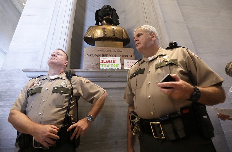 Tennessee State Troopers stand near a bust of Nathan Bedford Forrest after protesters covered it and placed signs in front of it Monday, Aug. 14, 2017, in Nashville, Tenn. Protesters called for the removal of the bust, which is displayed in the hallway outside the House and Senate chambers. Violence in Virginia this weekend has given rise to a new wave of efforts to remove or relocate Confederate monuments. (AP Photo/Mark Humphrey)