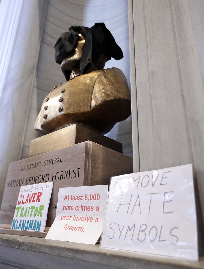 Signs stand in front of a bust of Nathan Bedford Forrest and a sweatshirt covers its face during a protest Monday, Aug. 14, 2017, in Nashville, Tenn. Protesters called for the removal of the bust, which is displayed in the hallway outside the House and Senate chambers. Violence in Virginia this weekend has given rise to a new wave of efforts to remove or relocate Confederate monuments. (AP Photo/Mark Humphrey)